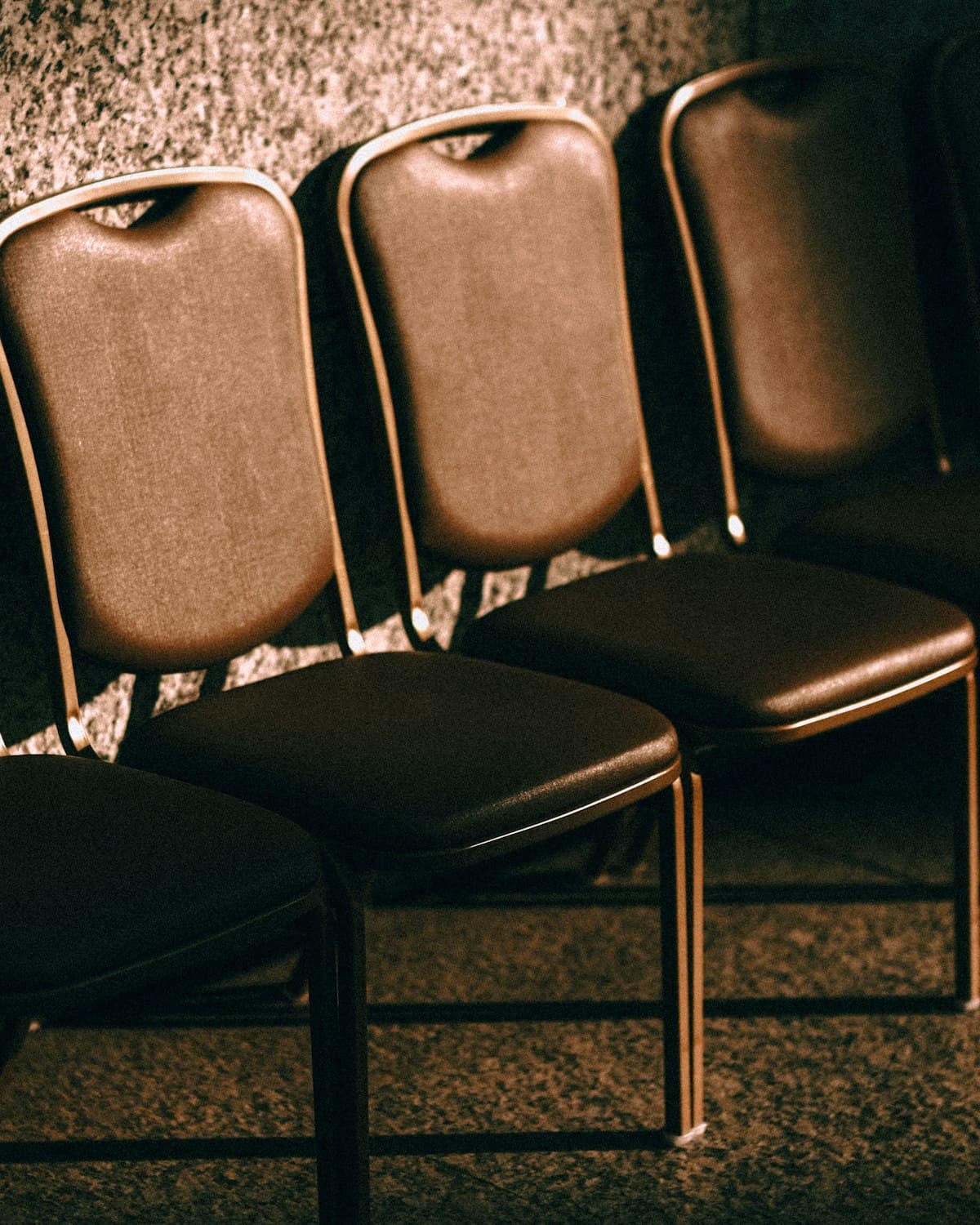 Empty brown leather chairs lined up against a wall in a corporate setting