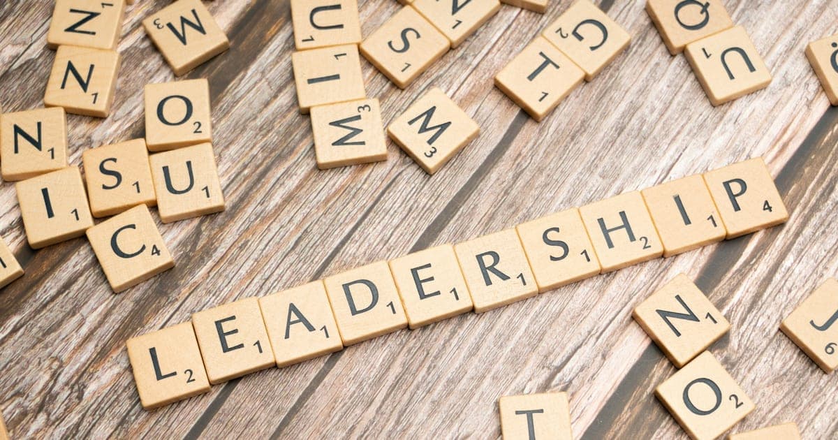 Scrabble tiles spelling out the word leadership on a wooden surface